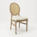 Silla Luis XV de resina con respaldo en bejuco sintético y asiento tapizado. Ideal para eventos en el exterior.
